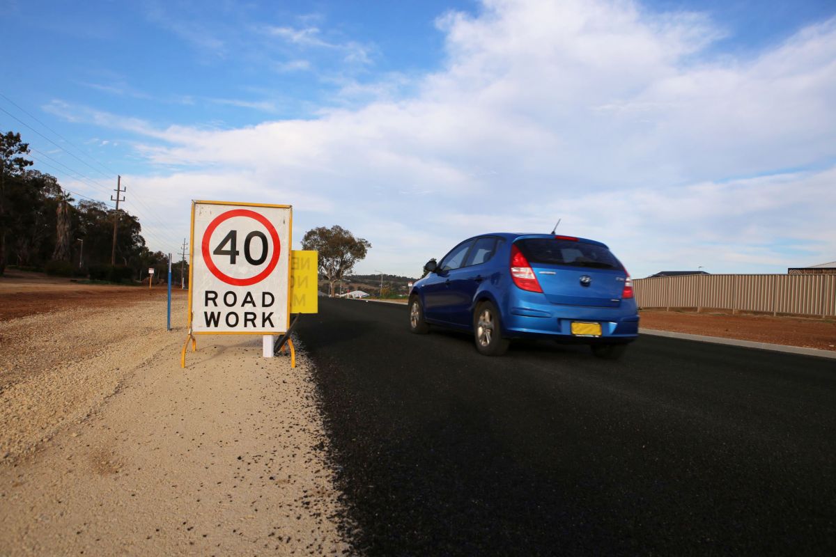 A blue car drives past a 40 km/hr road sign on the upgraded Farrer Road.