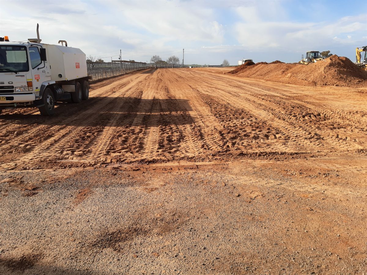 Construction site, water truck, earthworks, construction machinery in background