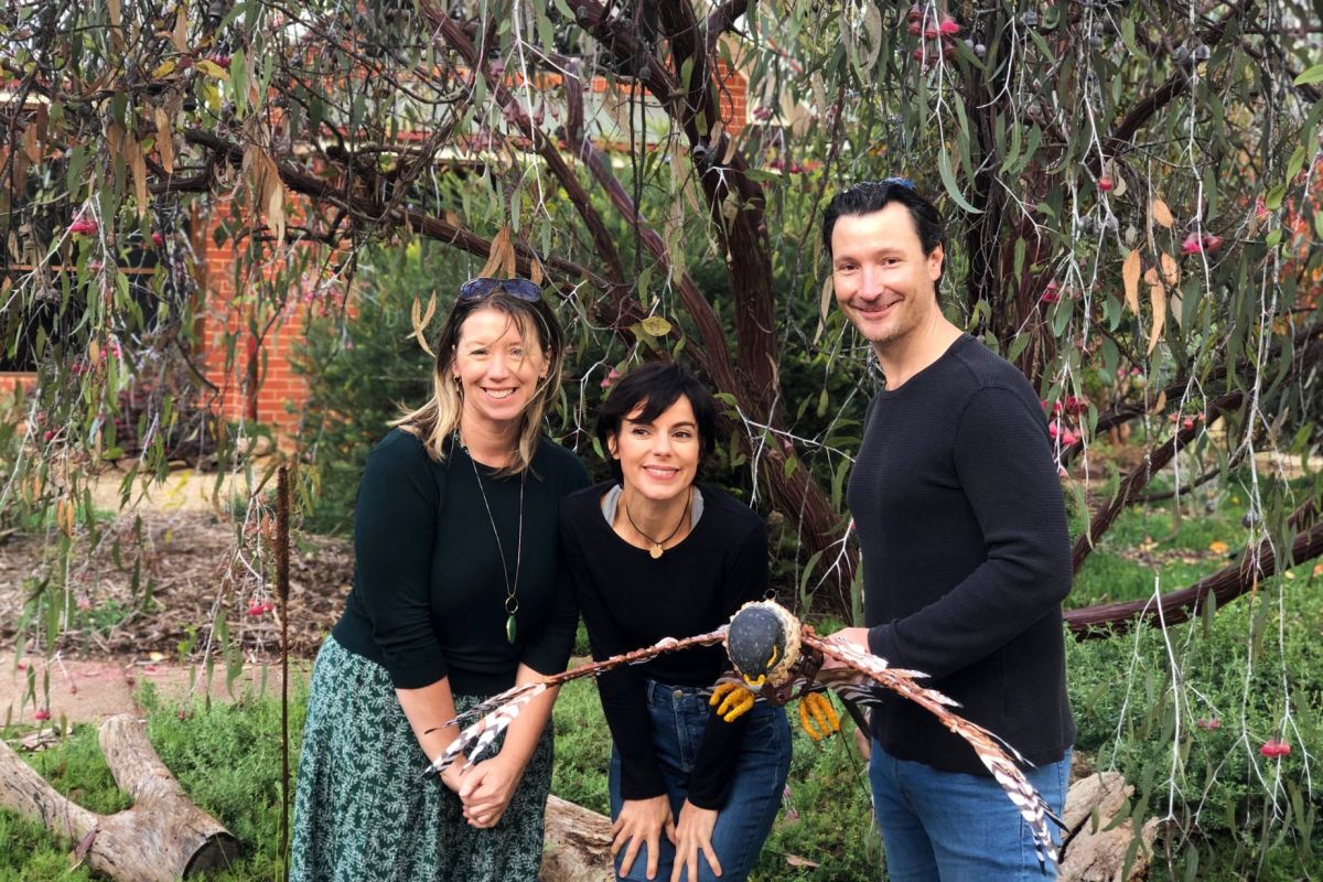 Two women and man holding a puppet bird