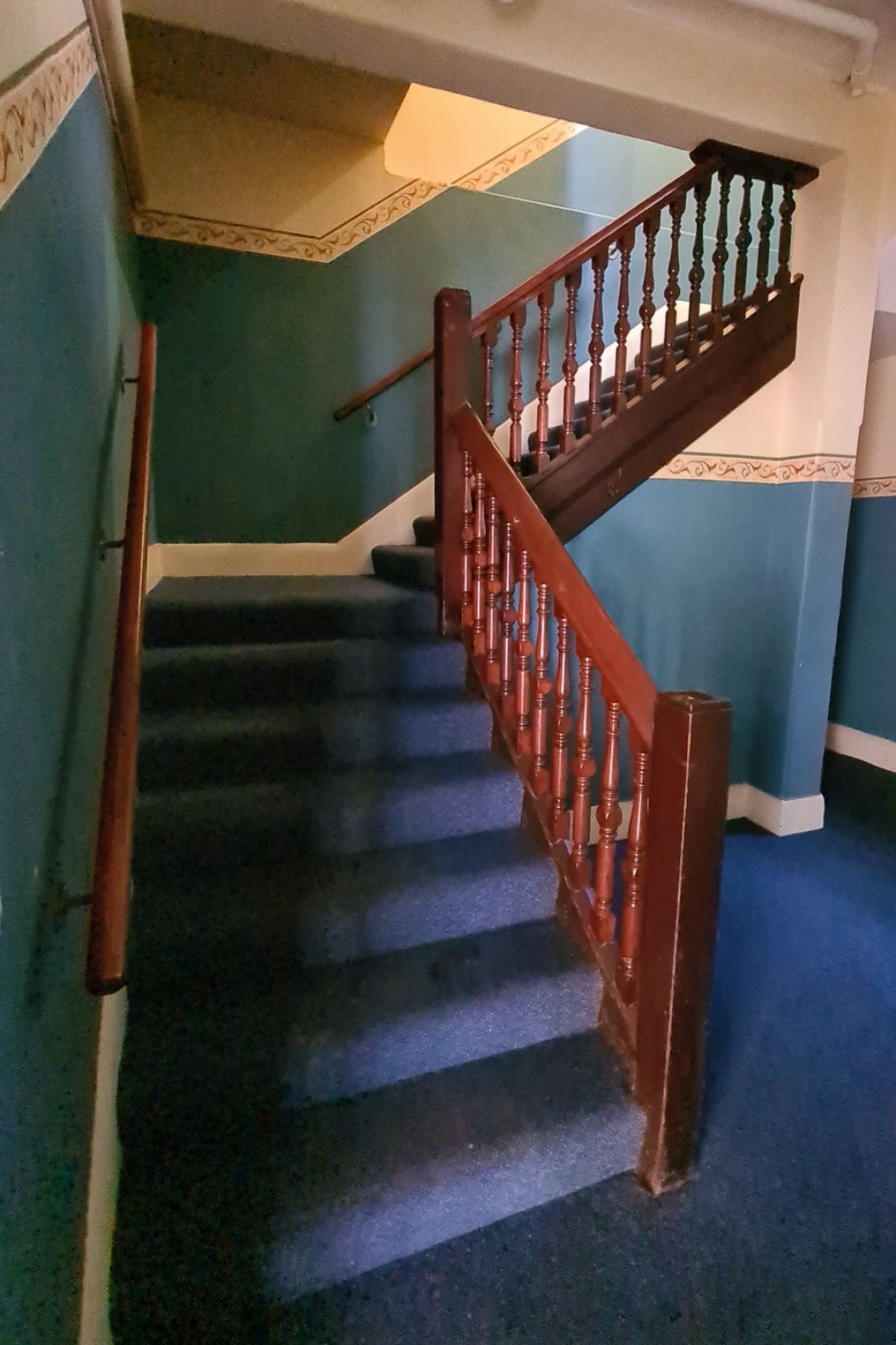 Stairwell with wooden hand rail and carpeted steps inside old ambulance station