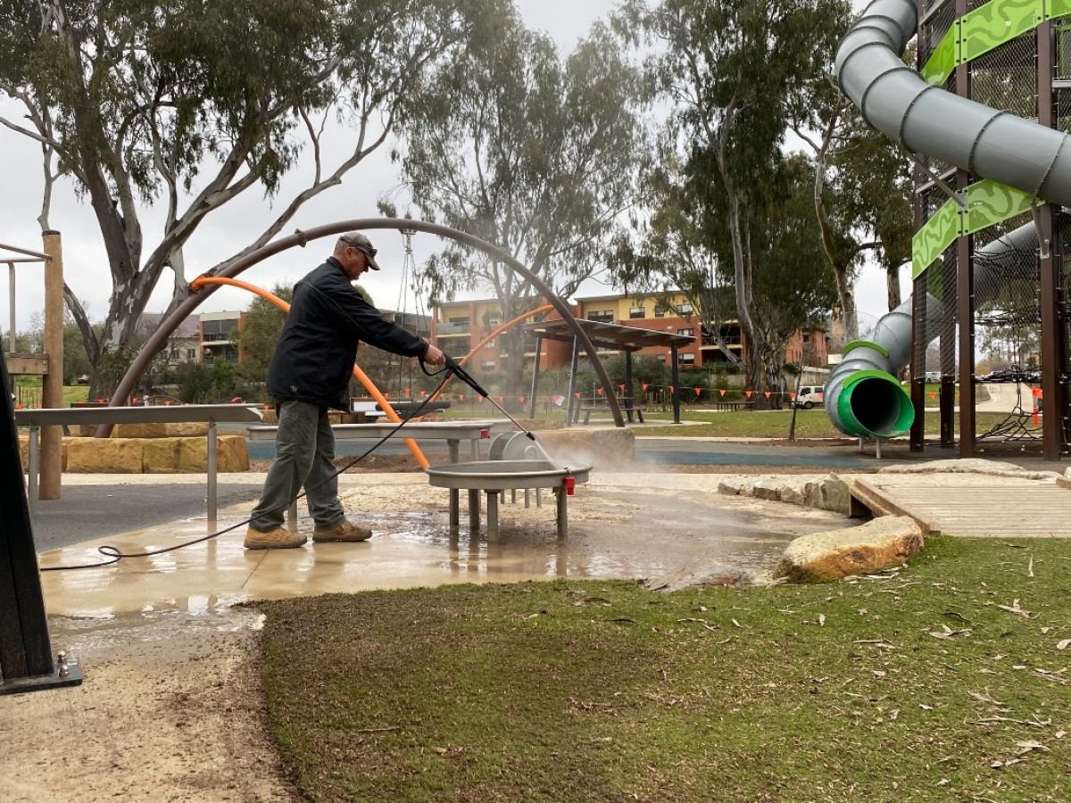 A man pressure washing play equipment