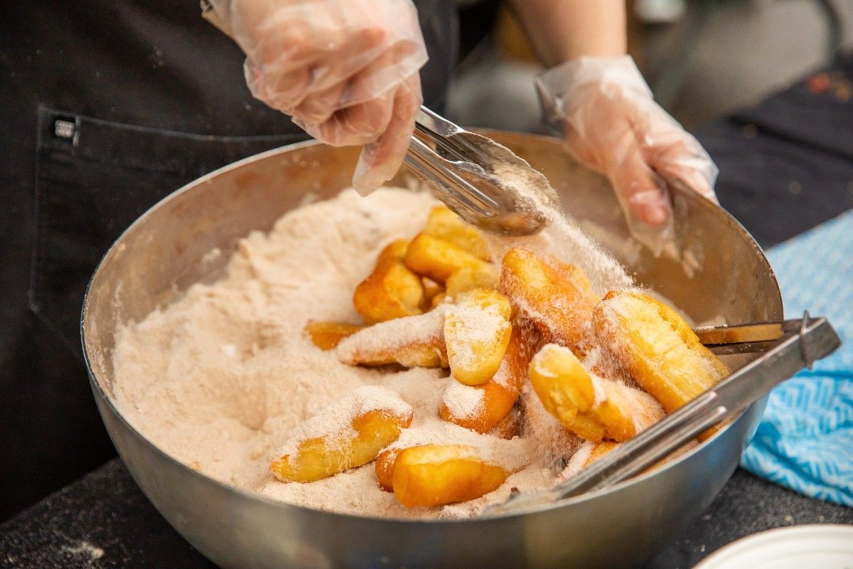 Churros being dipped in sugar coating