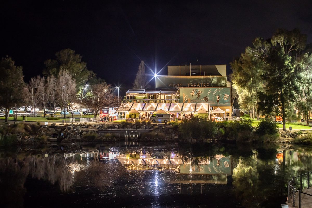 a festival at a theatre with outdoor facilities, photo taken from across a lagoon. 