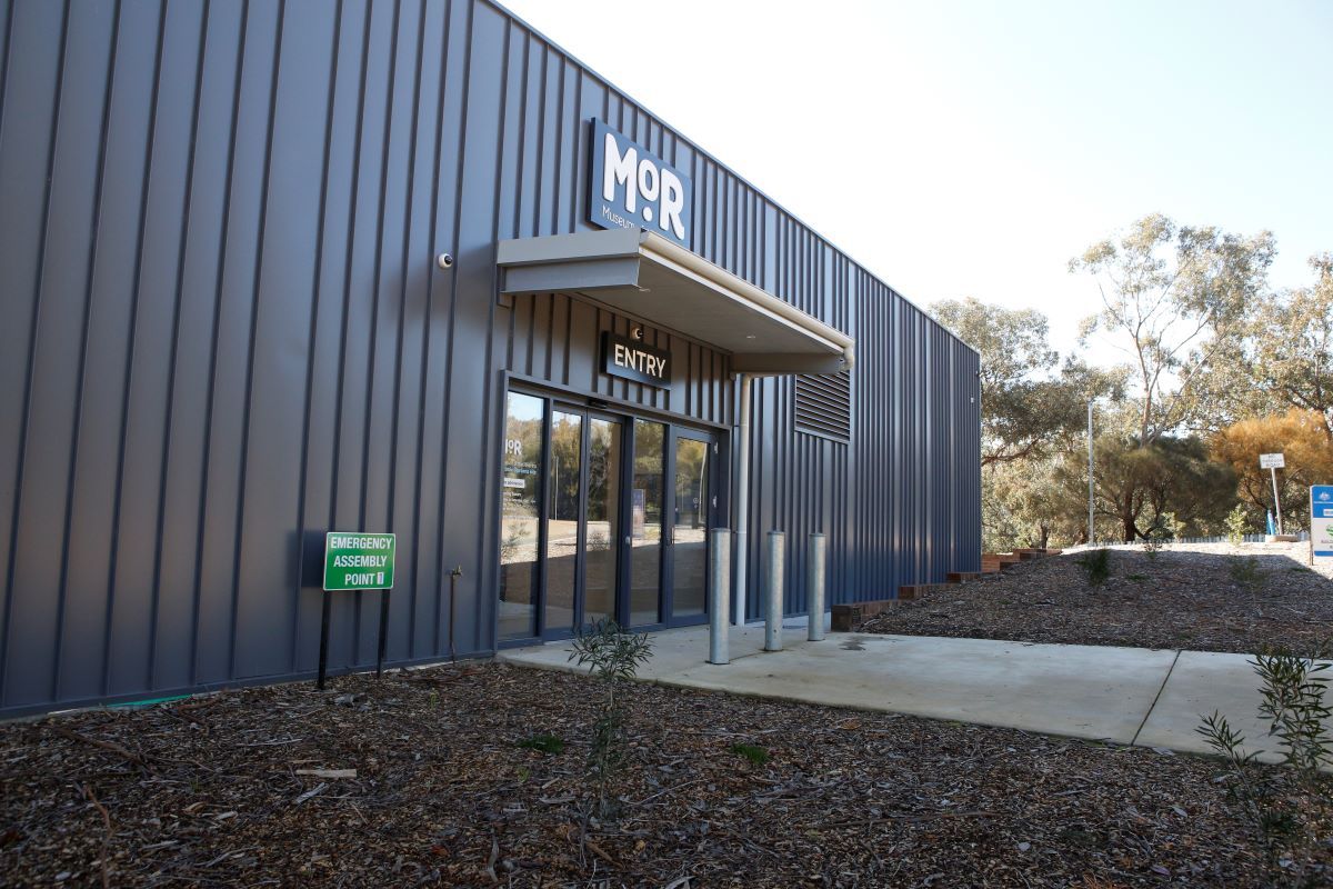 The facade of a building and a path leading to some glass doors. 