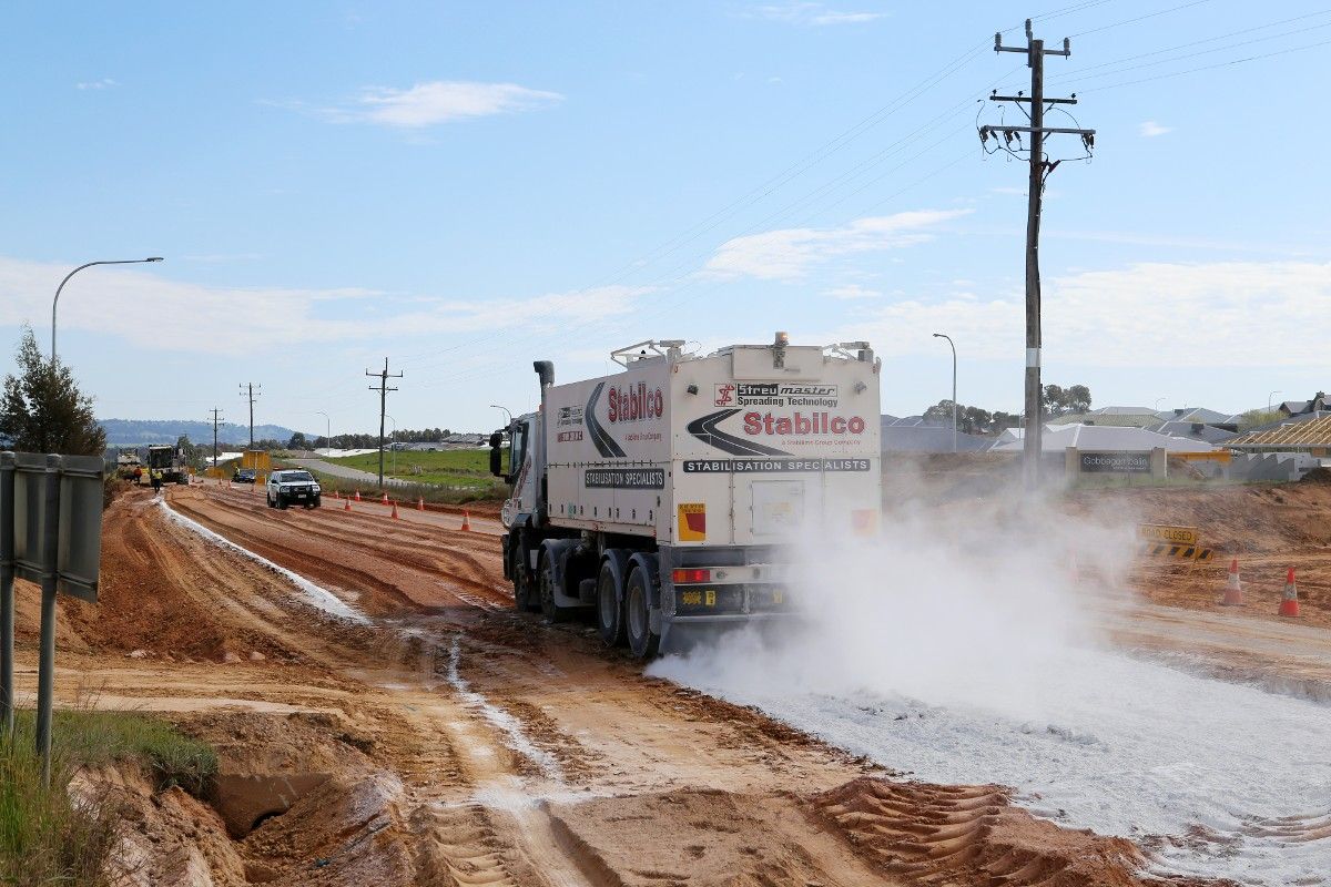 Truck spreading lime as part of road base stabilisation process