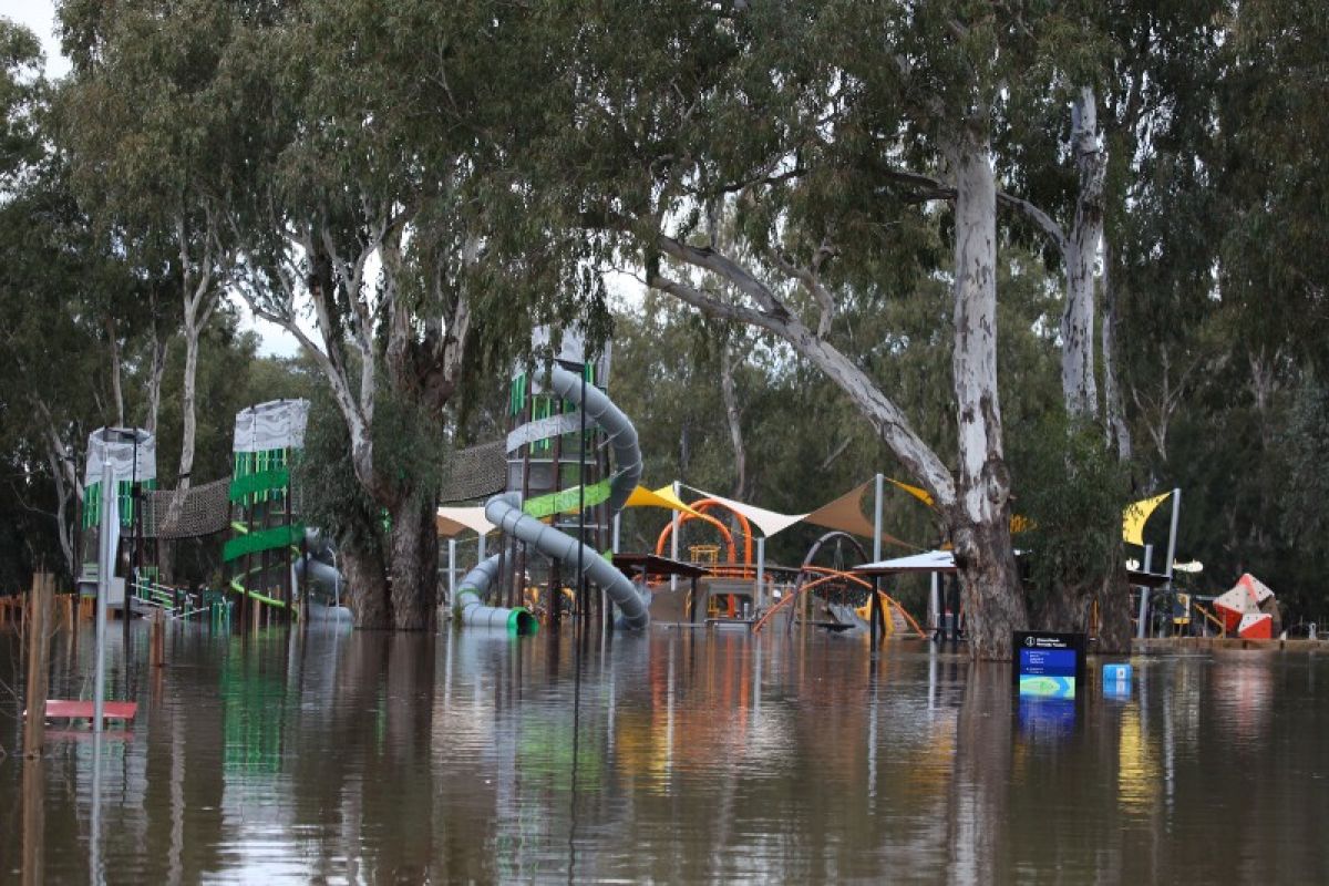 A large children's playground partially submerged in floodwaters. 