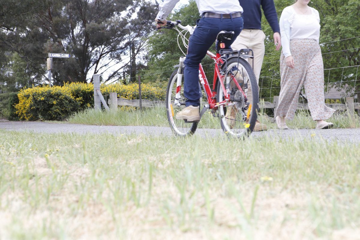 Close up of wheels as cyclist rides past pedestrians on a bitumen path