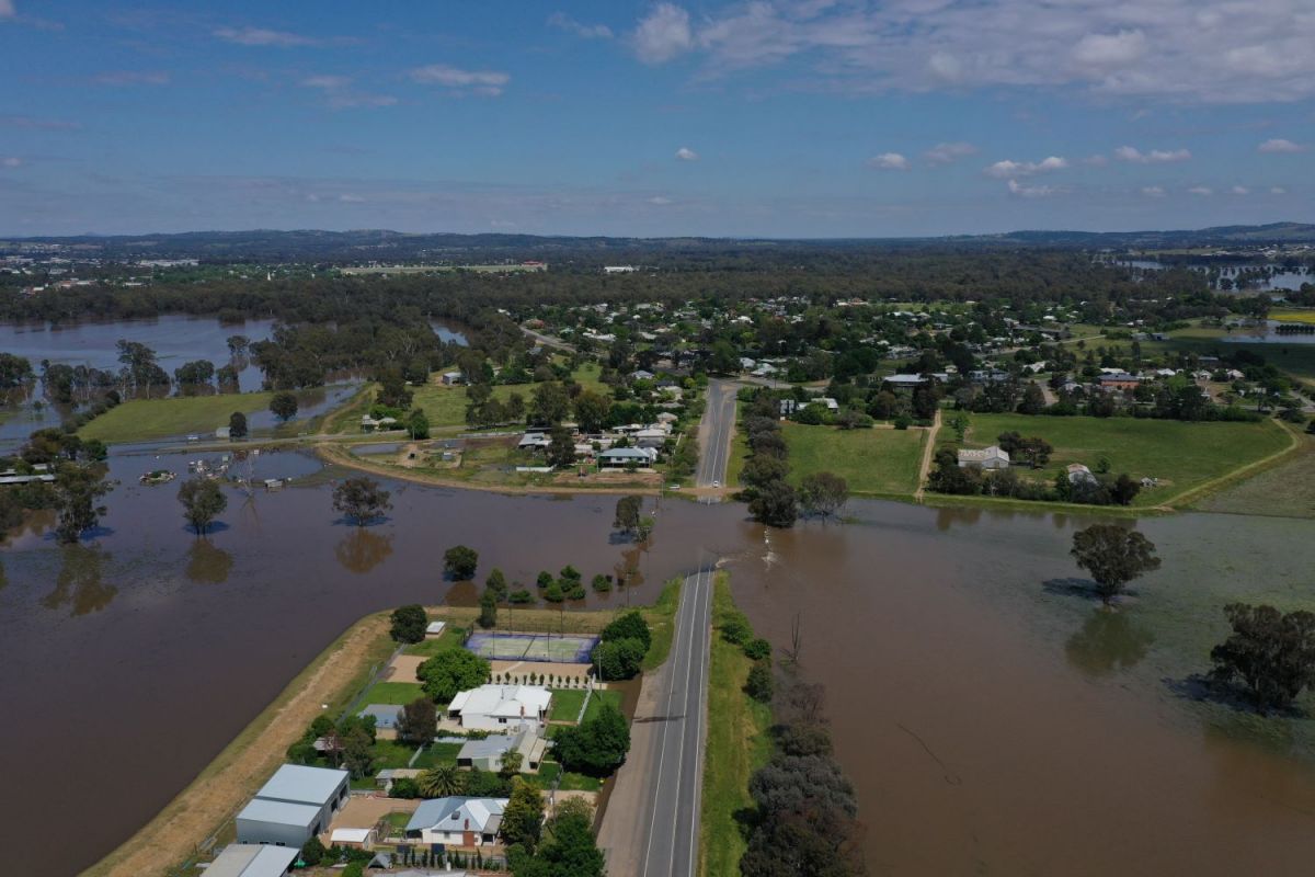 Drone image showing flood water over North Wagga road leading to suburban homes.