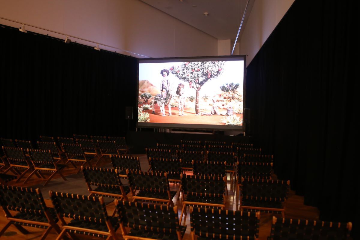 A darkened room with seats facing a large screen. On the screen is a stop-motion animation. 