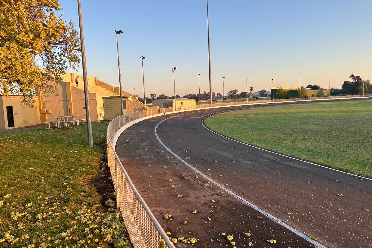 Cycling track around outside of oval curves off to the right, with an open concrete grandstand to the left of the track.