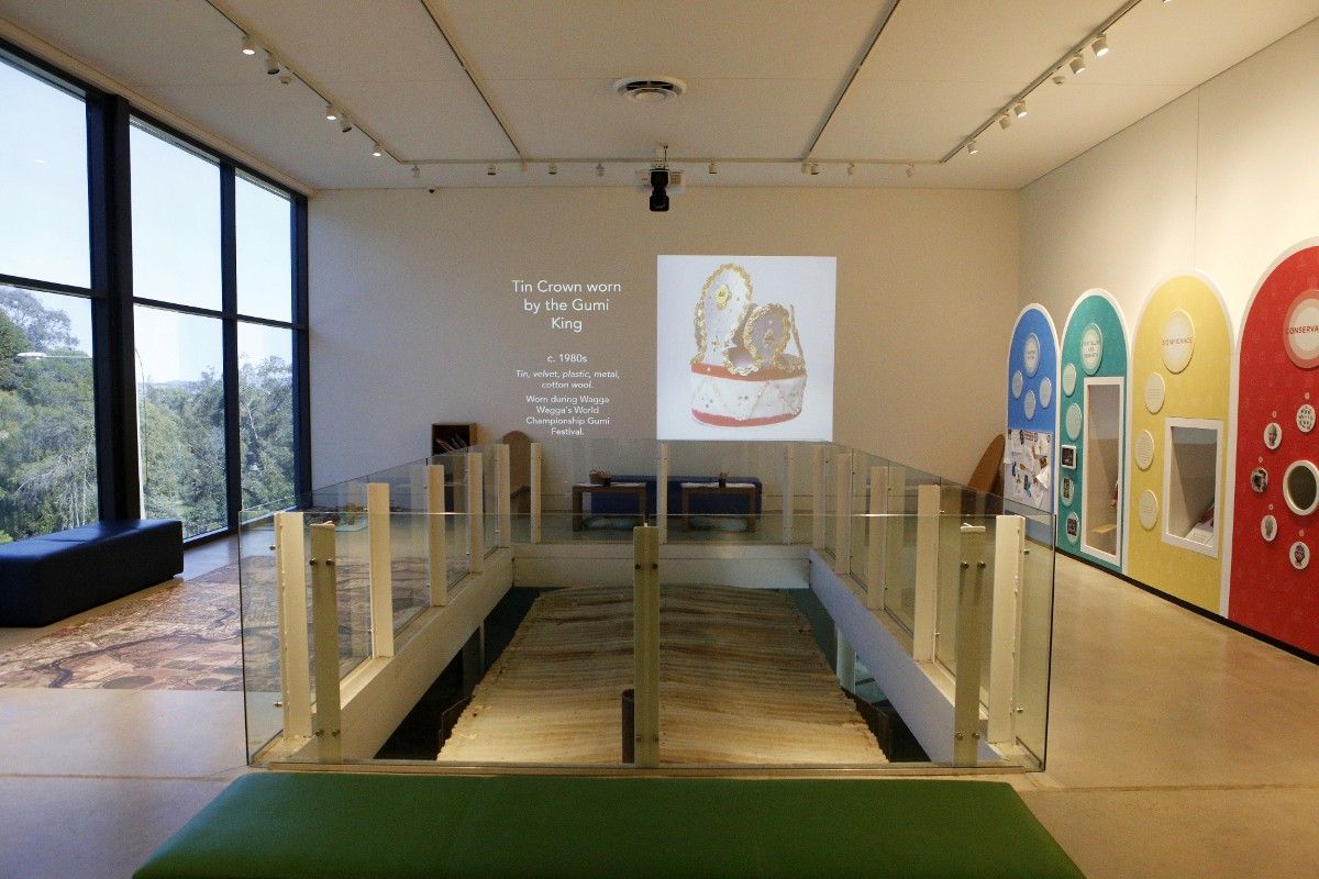 Open gallery space inside Museum of the Riverina, with displays on the right hand side and windows on the left, and projection on the rear wall.