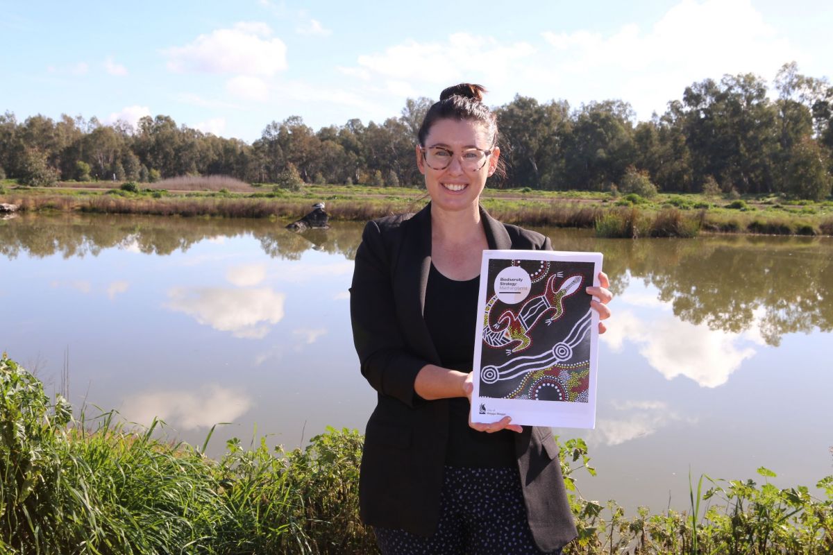 Woman standing in front of wetlands holding document