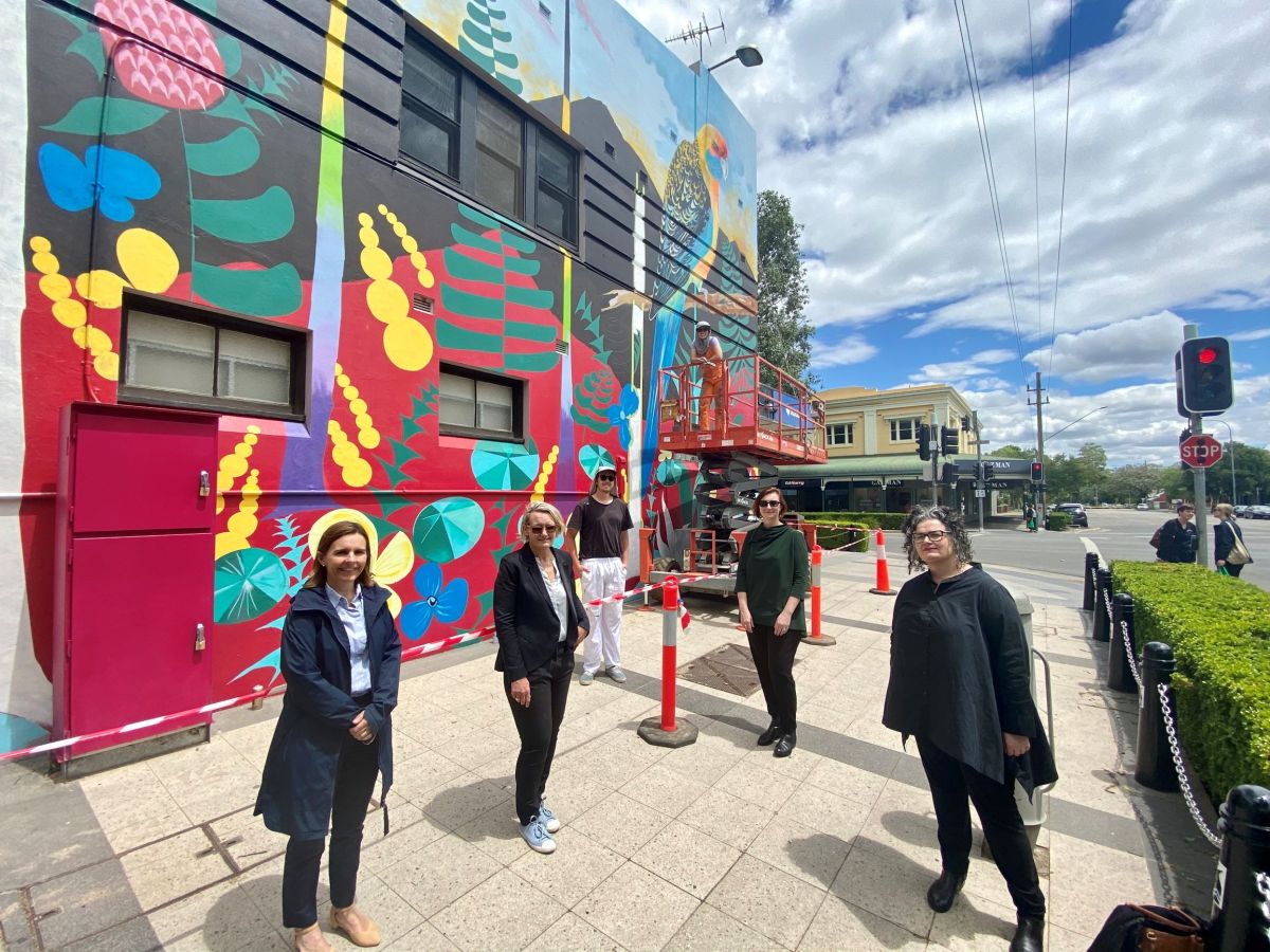 A group of people standing in front of a large mural