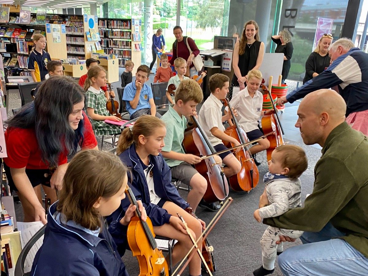 Children with instruments looking at a baby