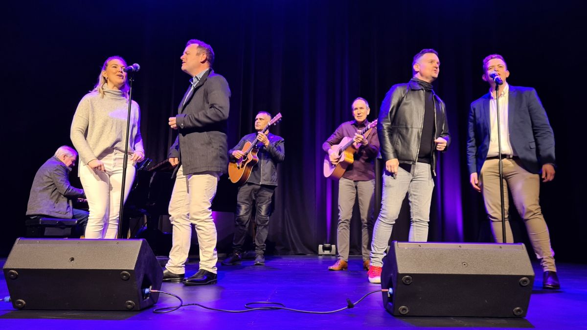 four singers, pianists and two guitarists on stage performing