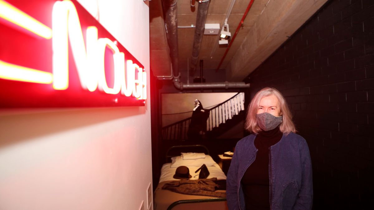 Woman standing beside neon sign saying ENOUGH