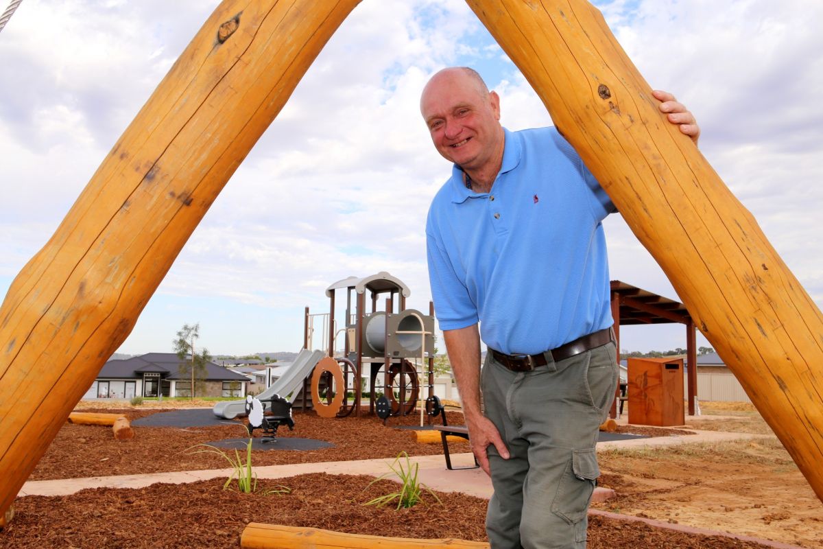 Man standing under piece of playground equipment