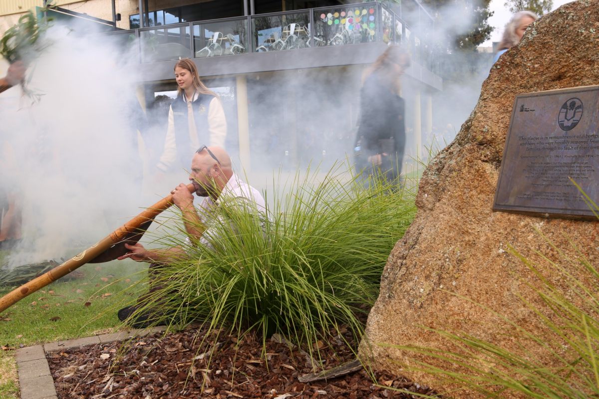 Didgeridoo players next Sorry Day Rock with smoking ceremony in background