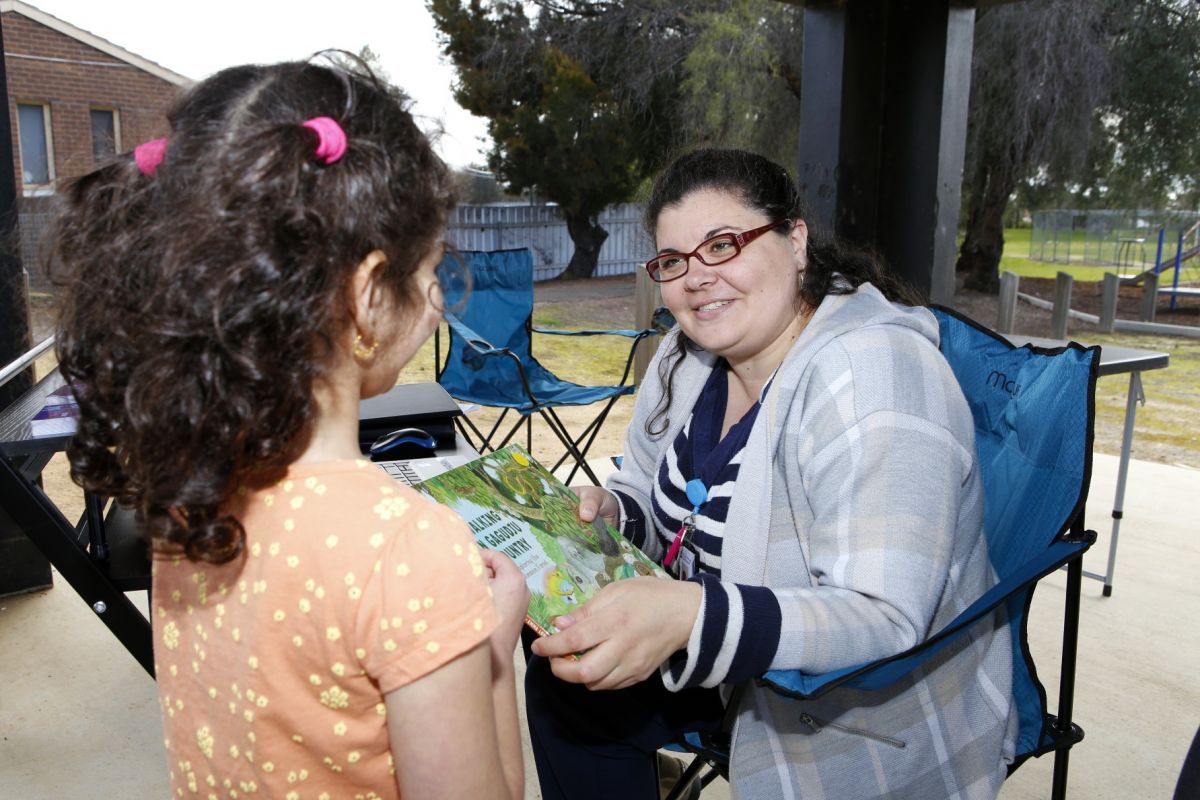 Female library officer with young girl at Agile Library tech station