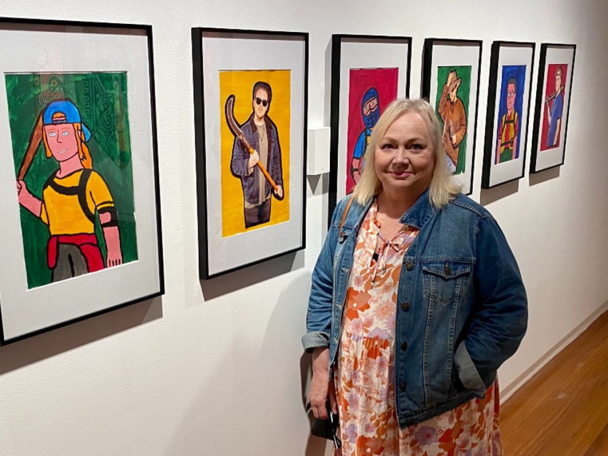  A woman stands beside a series of artworks