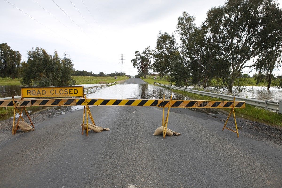 Road Closed sign with flooded road in background