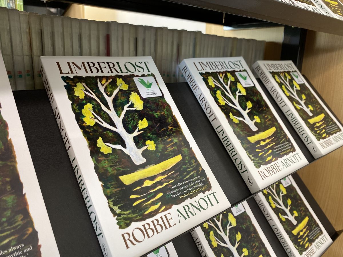 Multiple copies of a book entitled 'Limberlost' by author Robbie Arnott lay on a library shelf.