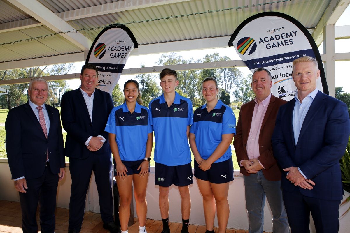 Four adult males standing with three teenaged athletes in uniform