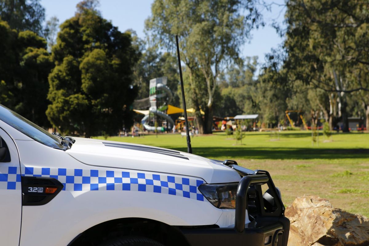 Front end of police van with Riverside playground in background