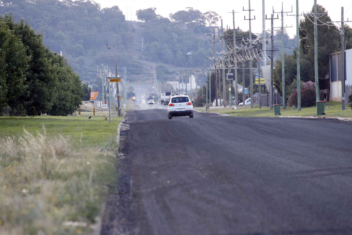 White vehicle driving on freshly sealed road