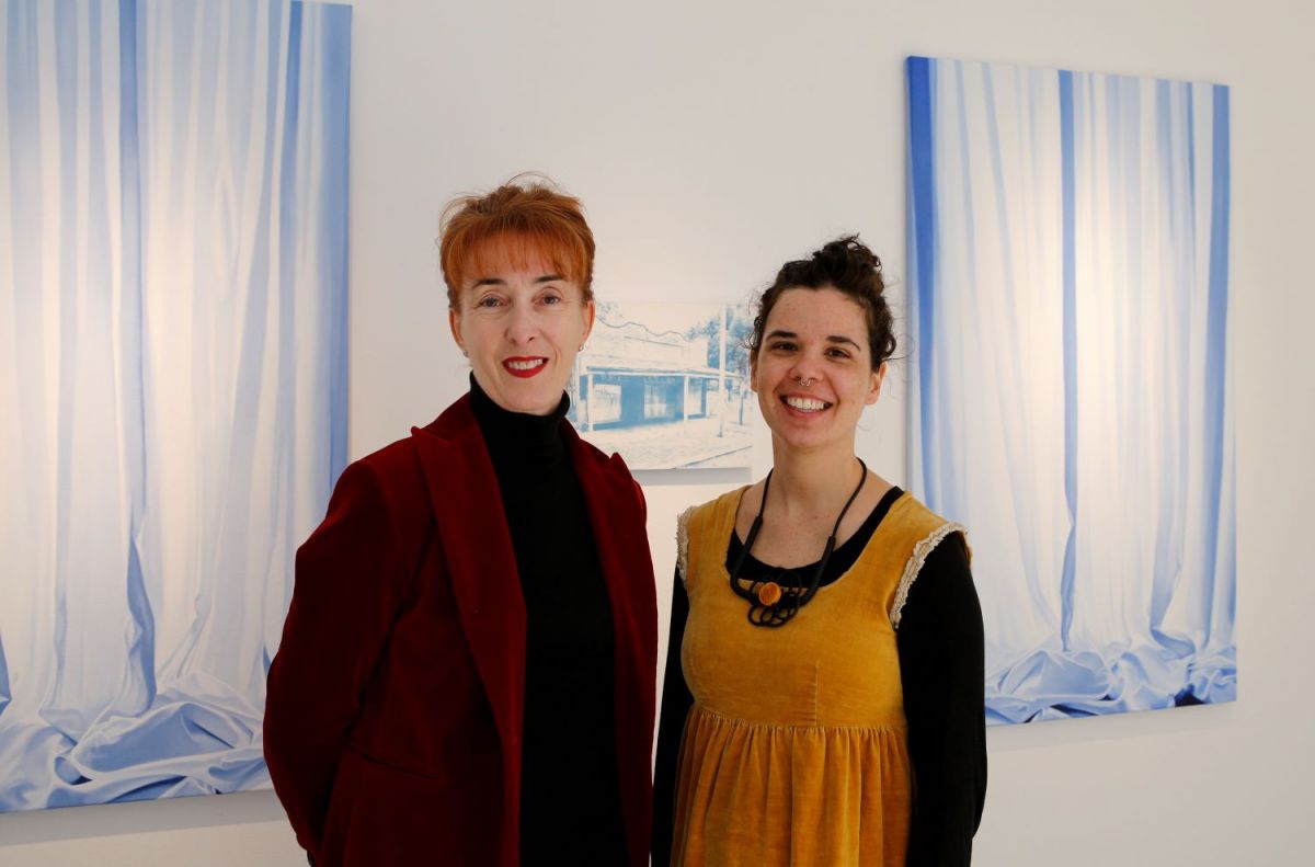 two women standing in front of some artworks