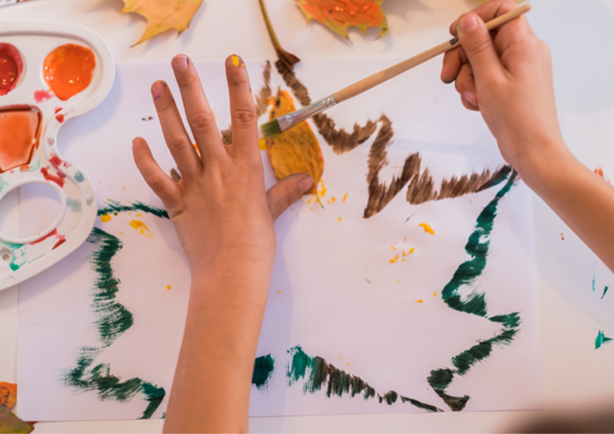 close-up of child's hands painting with leaves. 