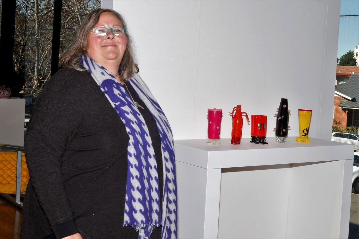 a woman standing with some of her plastic artworks.