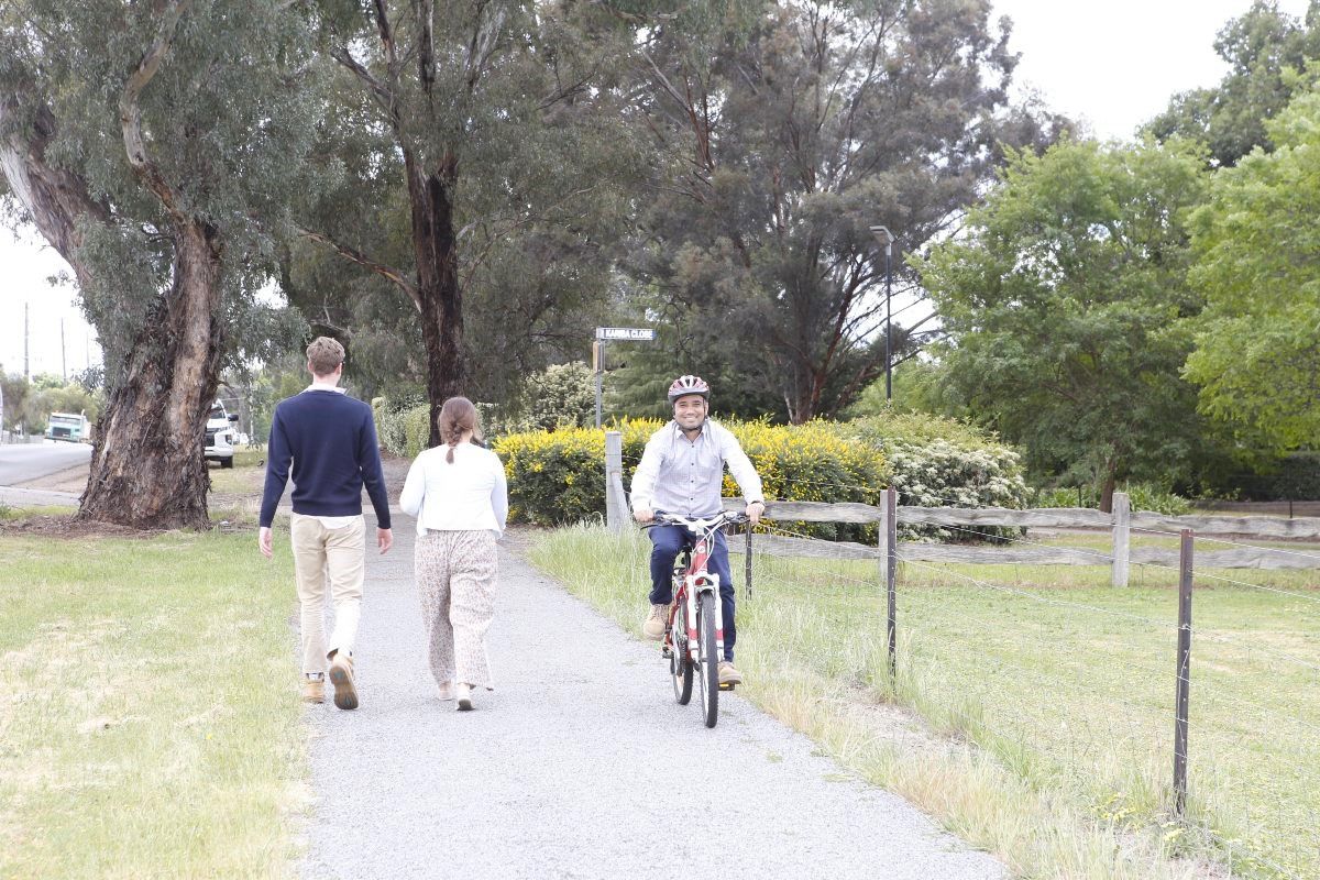 Man and woman walking along path, and being passed by man on bike