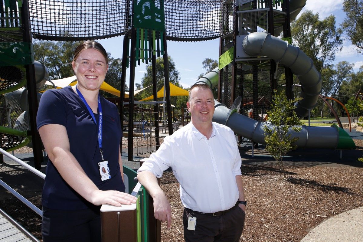 Woman and man standing in front of tower slides with more playground equipment in the background