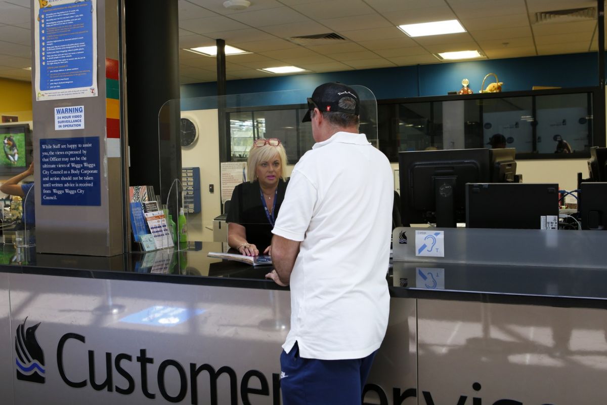Woman in council shirt talking to man in tee shirt on other side of Customer Service desk