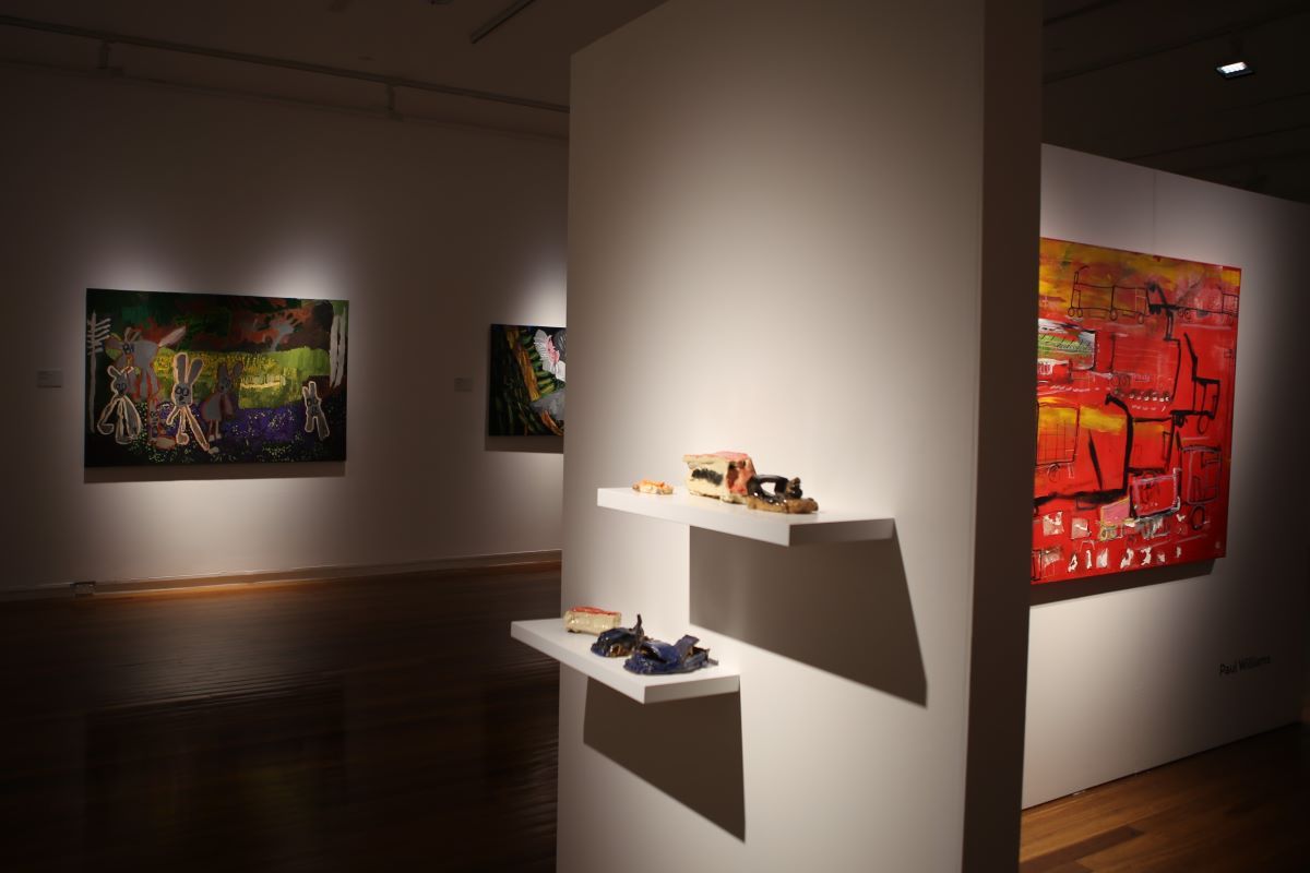 An exhibition with colourful artworks and ceramics. 