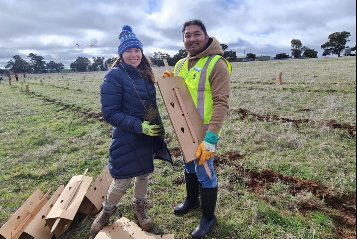 A female and male outside holding planting materials.