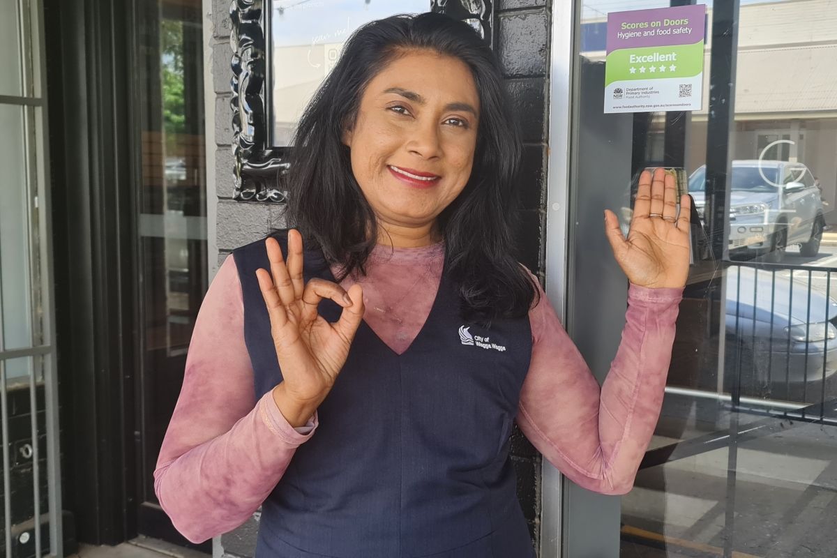 Wagga Wagga City Council Environmental Health Coordinator Sharomi Dayanand showing highest rating sticker – ‘Excellent’ – for food safety and good hygiene outside of 'Guiseppe's' on Kinkaid St