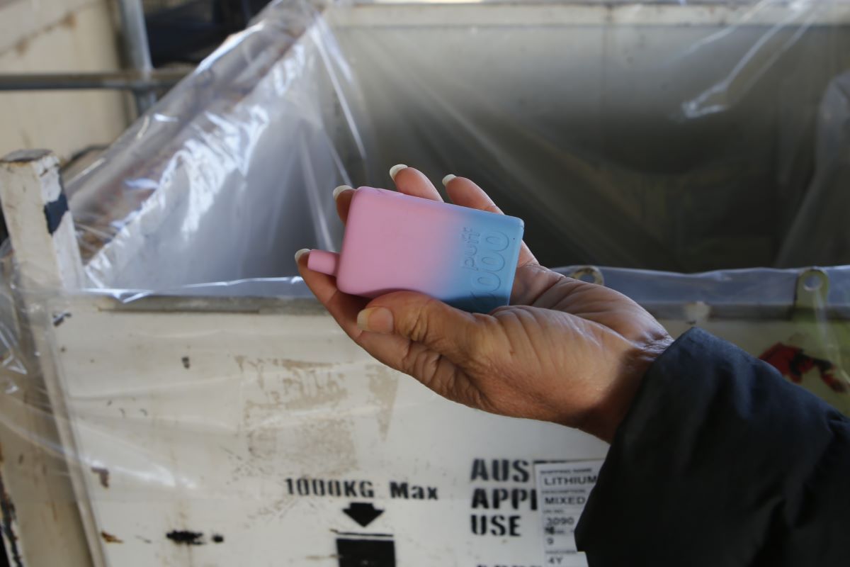 A woman's hand holding a pink and blue vape.