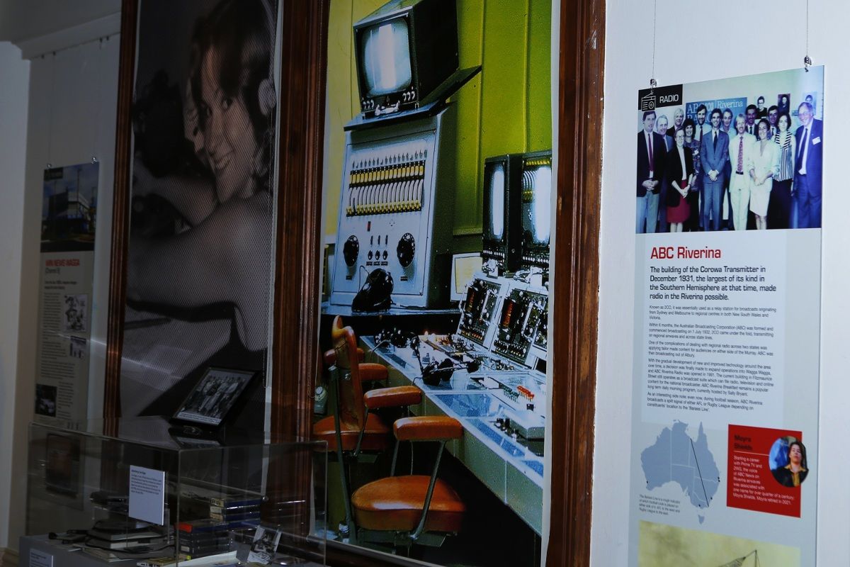 Large picture on museum wall of a TV studio from analogue days, with screens and tape editing machines, and a didactic panel detailing the history of ABC Riverina.