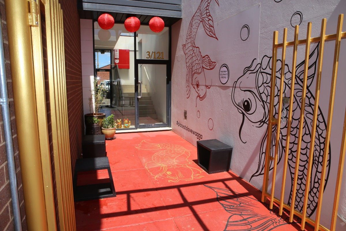 A small open space with plants, seating and a koi-themed mural