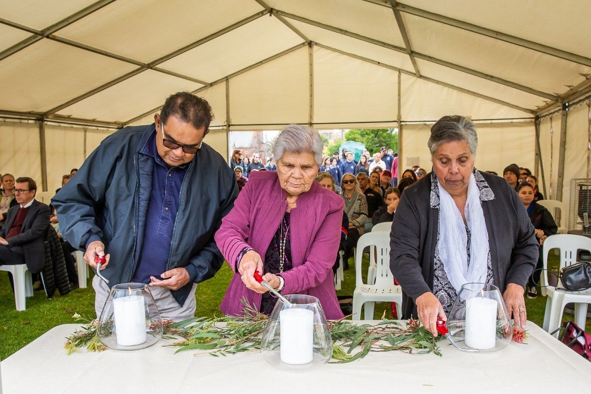 Three people lighting hurricane lamps