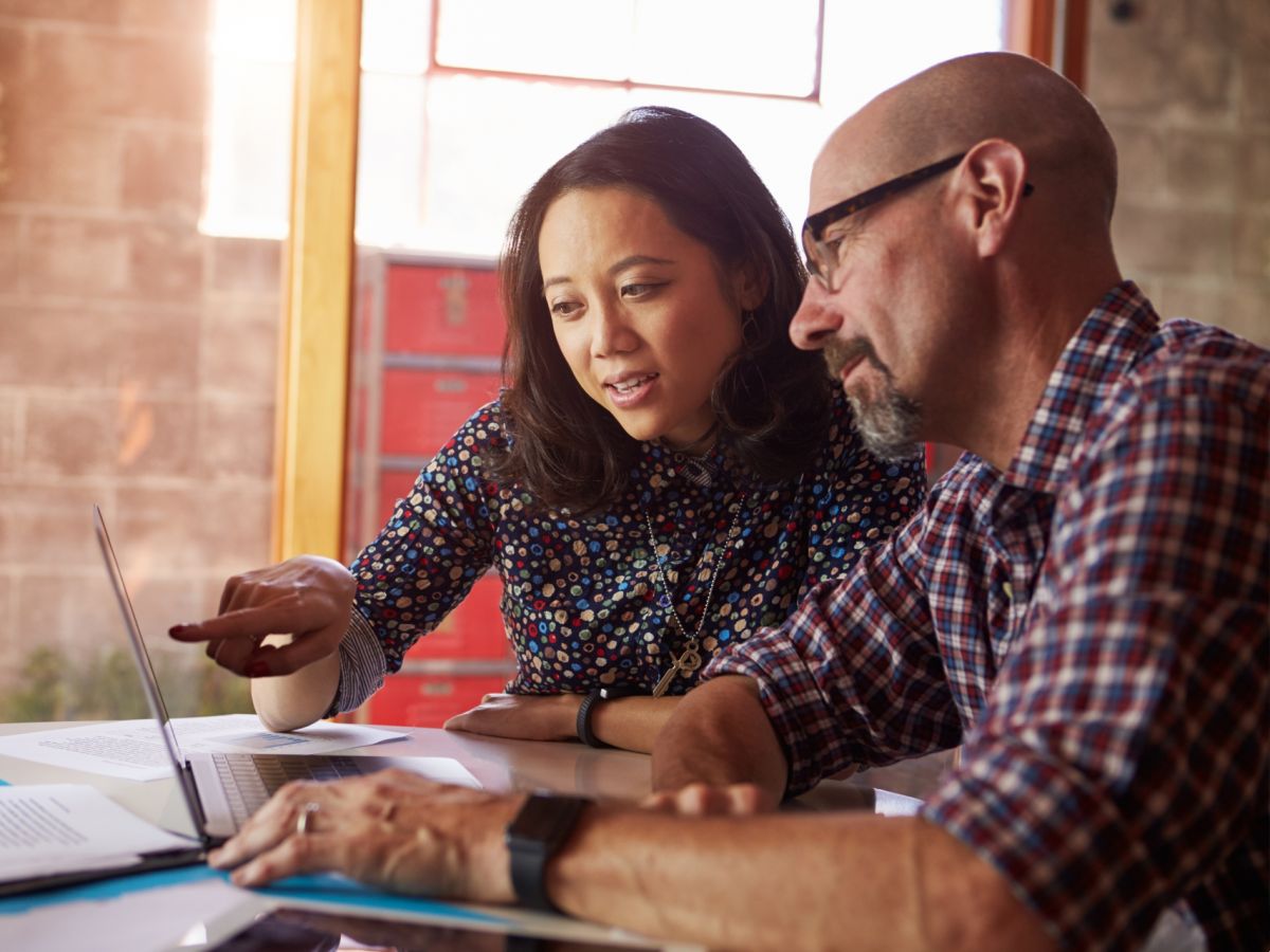 Woman and man at desk with laptop open in front of them