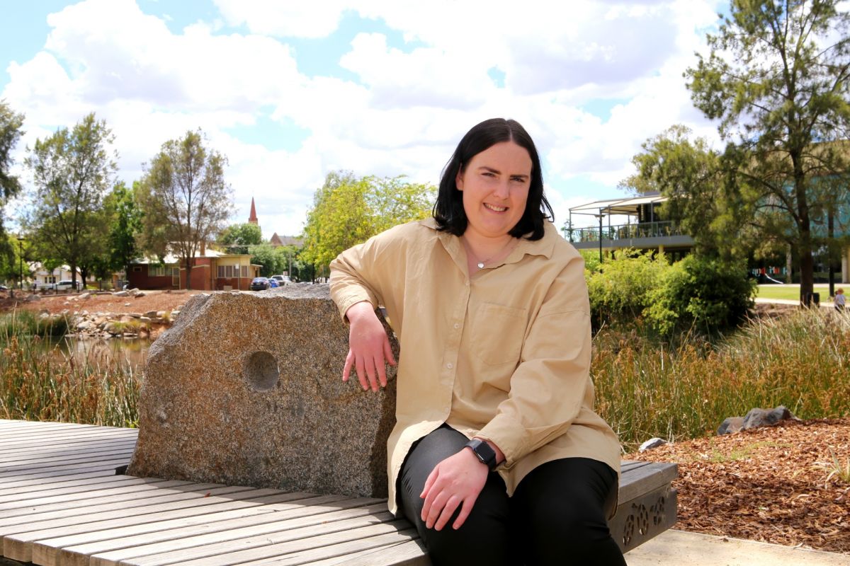 Woman sitting on bench beside lagoon