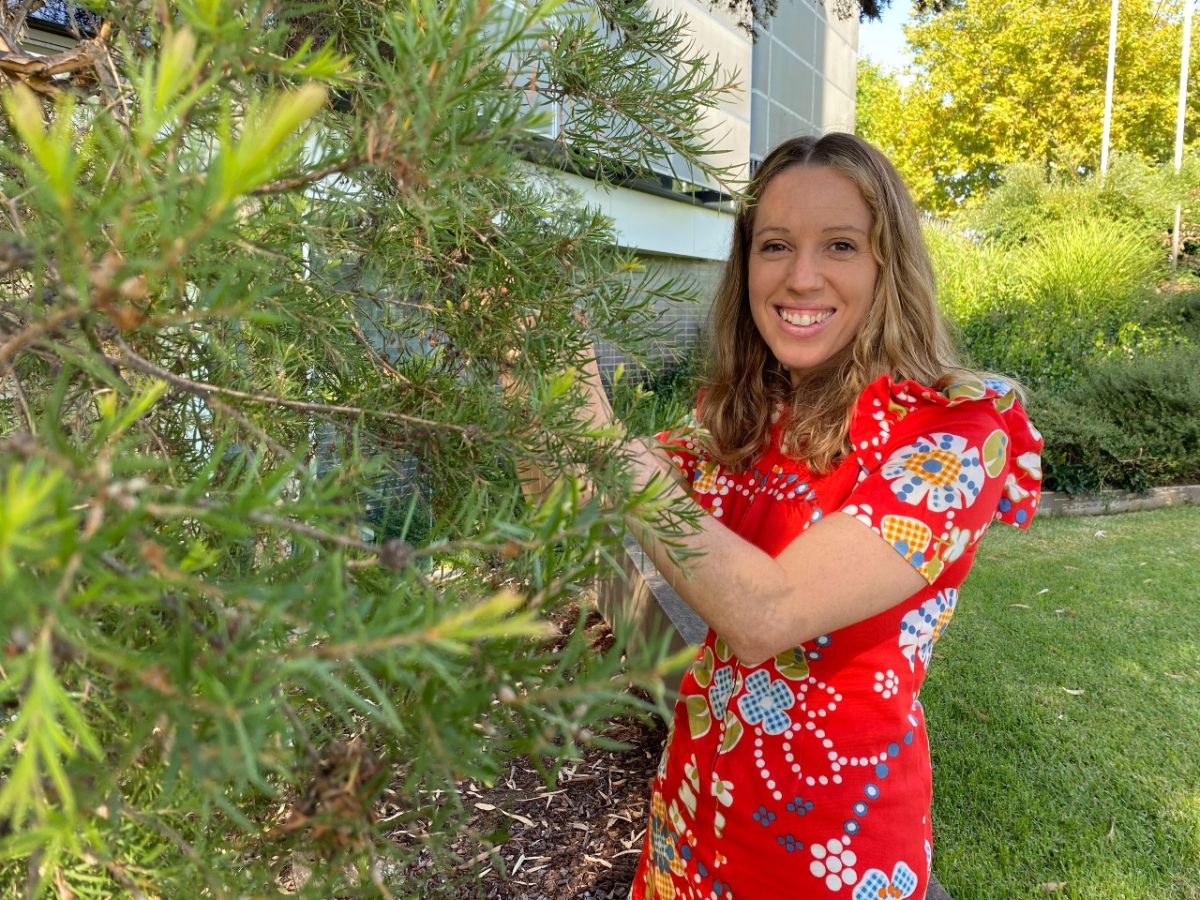 Woman in a red dress standing beside an Australian native 