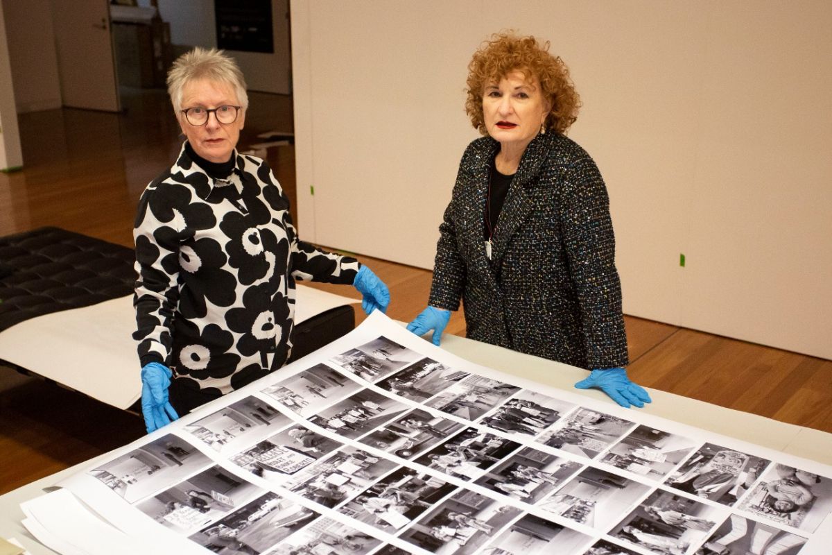 Two women stand at a table covered in black and white images