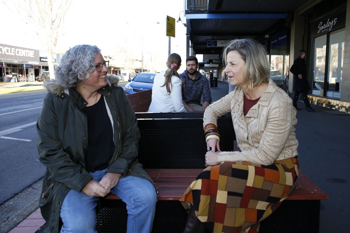 Two woman sitting on parklet in main street