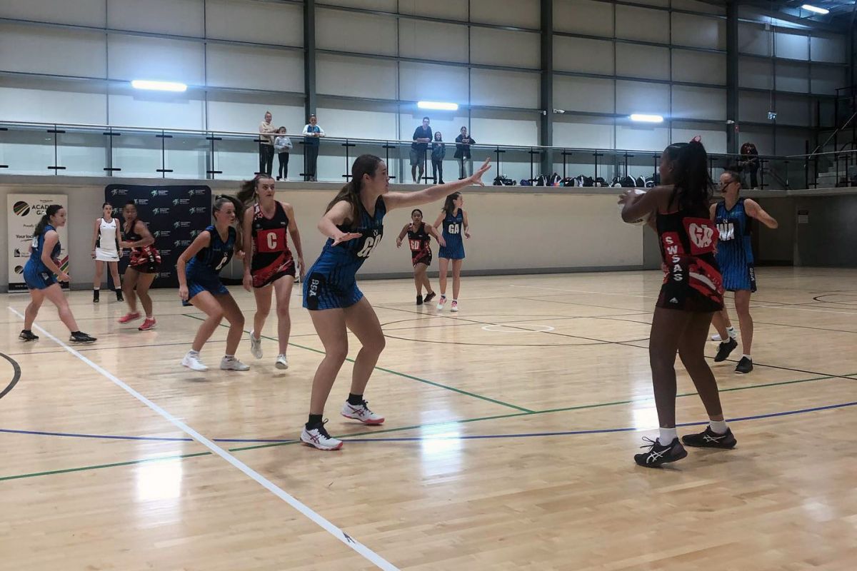 Girls playing netball on indoor court