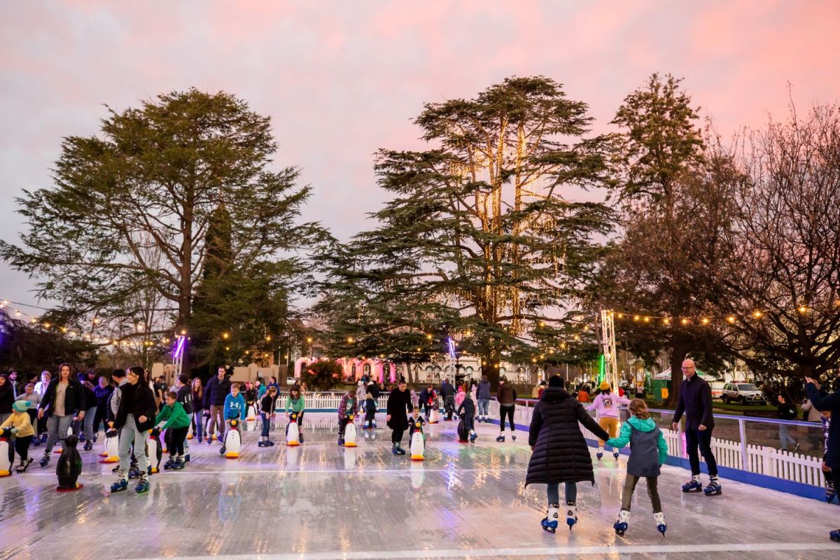 Adults and children skating on an outdoor ice skating rink.