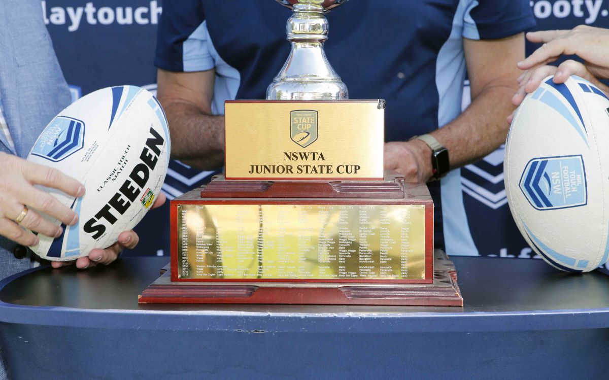 Gold coloured trophy on table with two touch footballs resting on either side of it